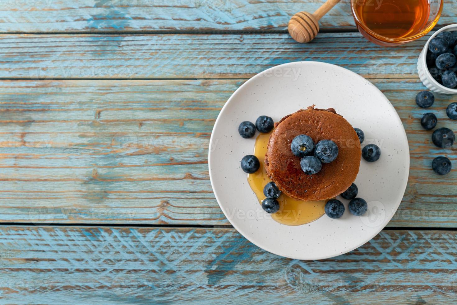 Chocolate pancake stack with blueberry and honey on a plate photo