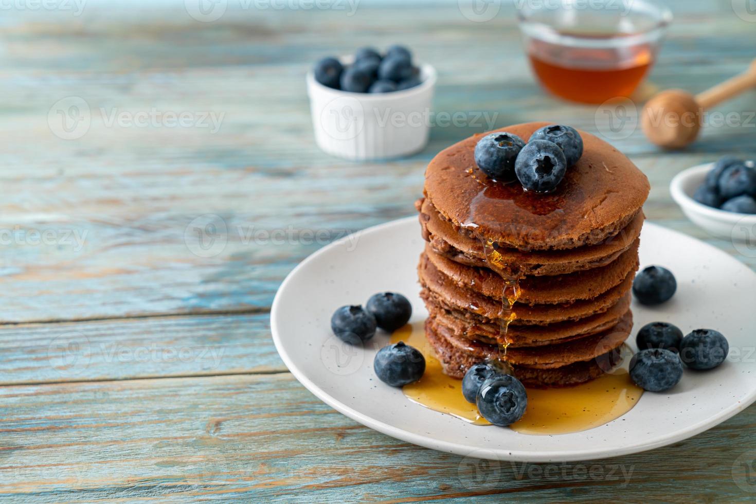 Chocolate pancake stack with blueberry and honey on a plate photo