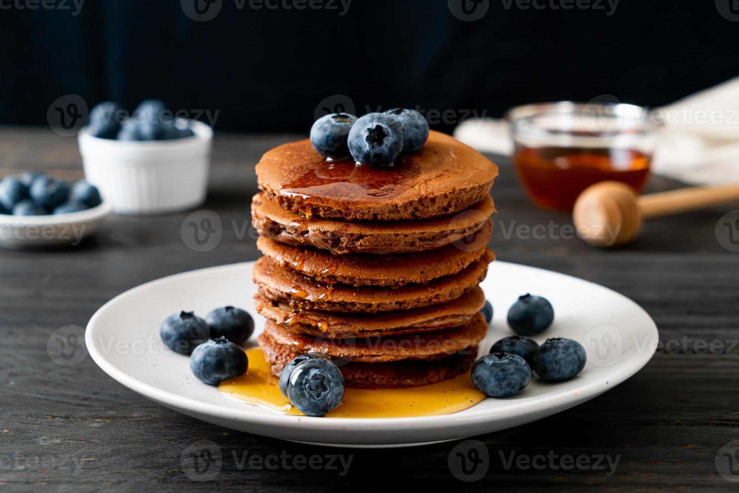 Chocolate pancake stack with blueberry and honey on a plate photo