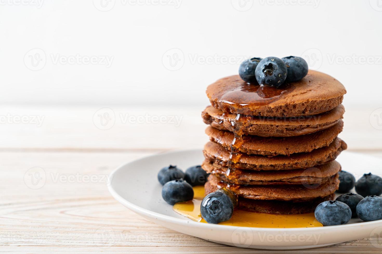 Chocolate pancake stack with blueberry and honey on a plate photo