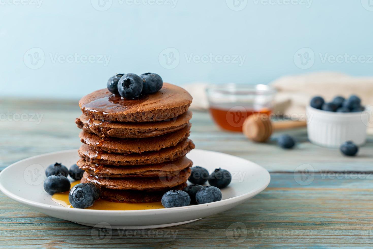 Chocolate pancake stack with blueberry and honey on a plate photo