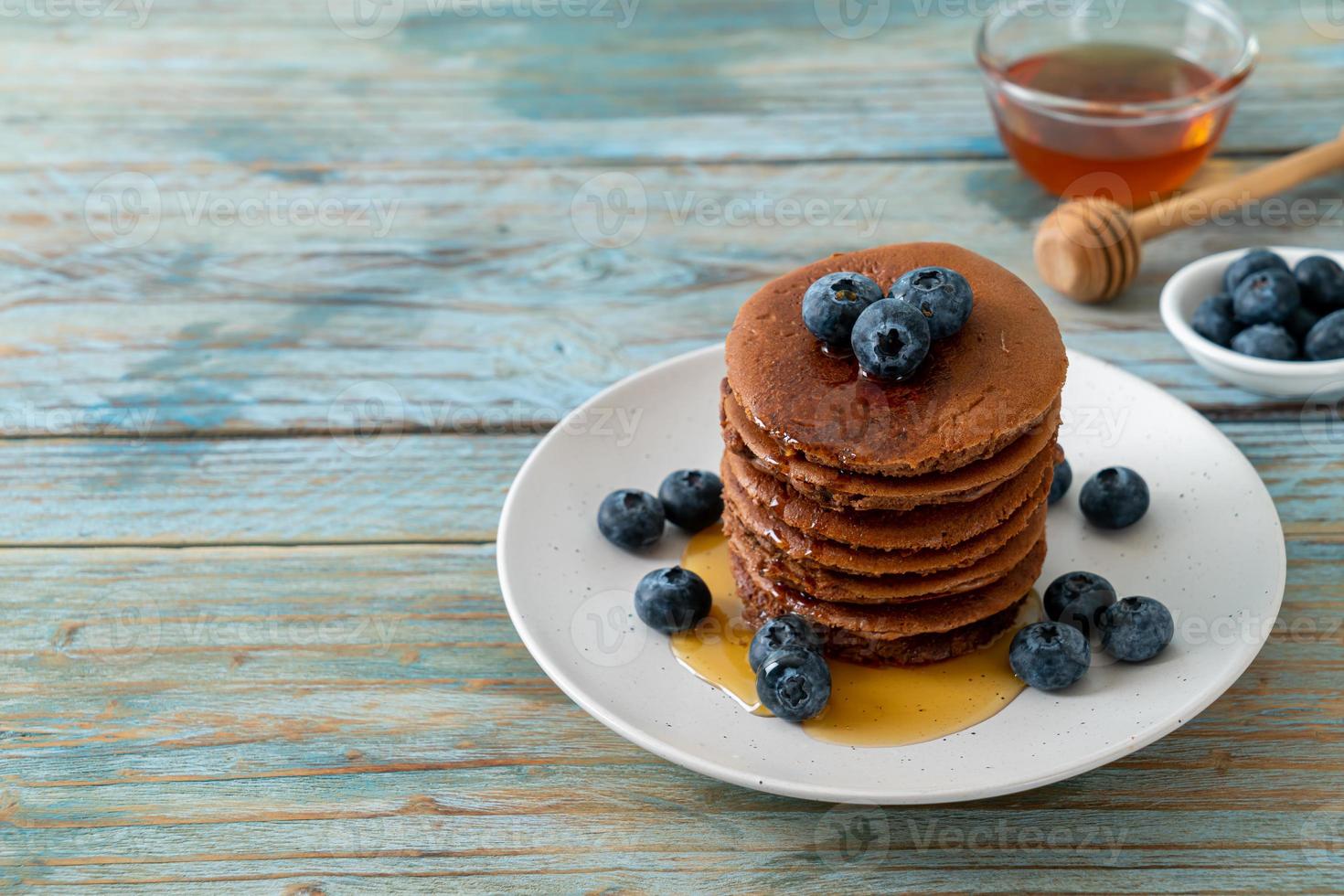 Chocolate pancake stack with blueberry and honey on a plate photo