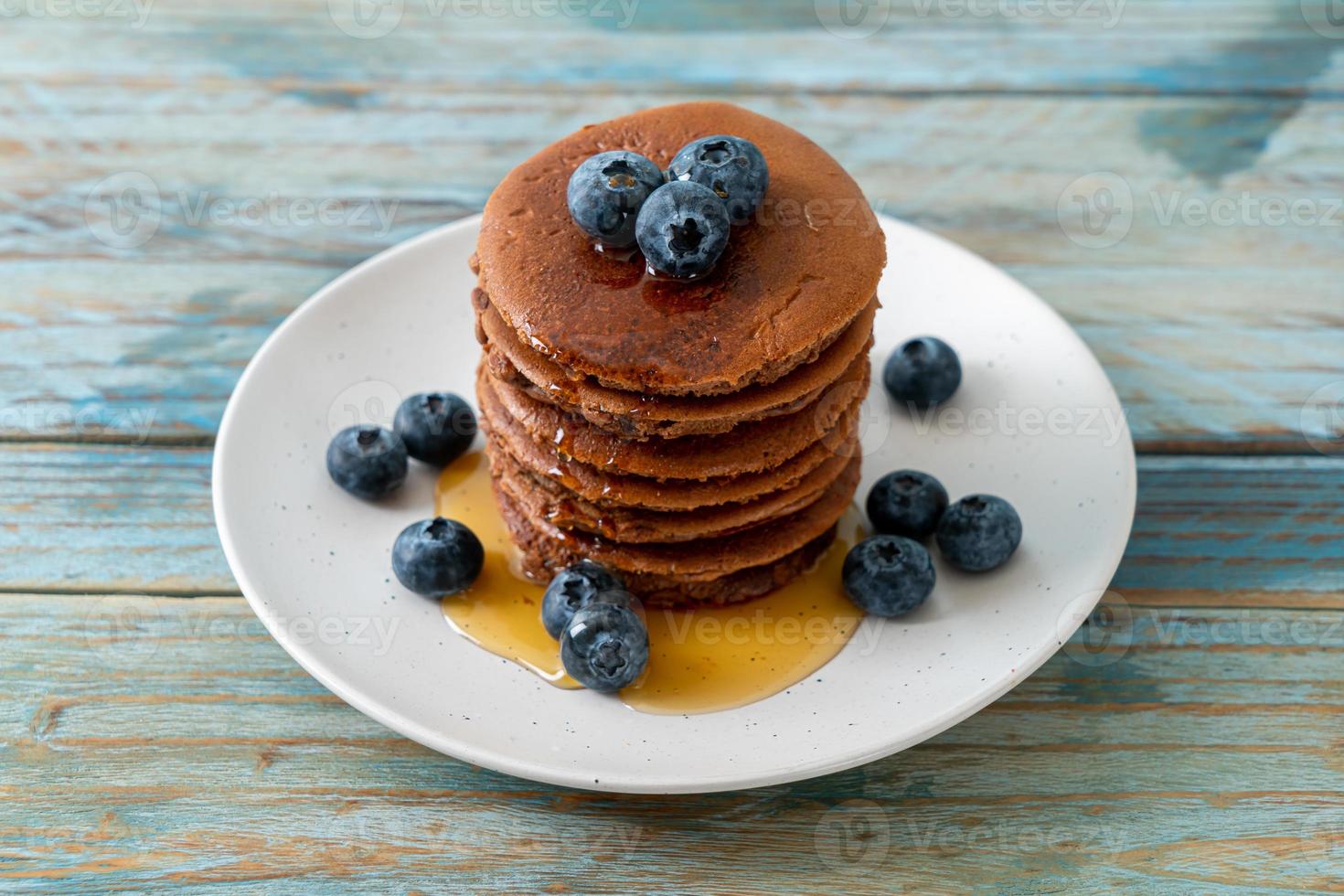 Chocolate pancake stack with blueberry and honey on a plate photo