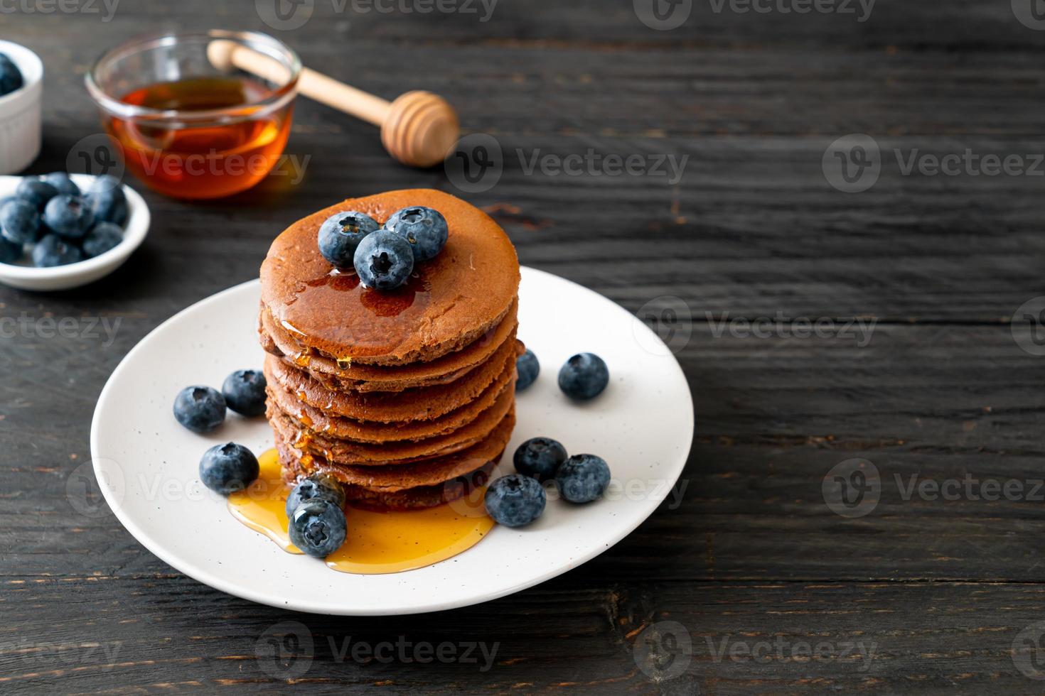 Chocolate pancake stack with blueberry and honey on a plate photo
