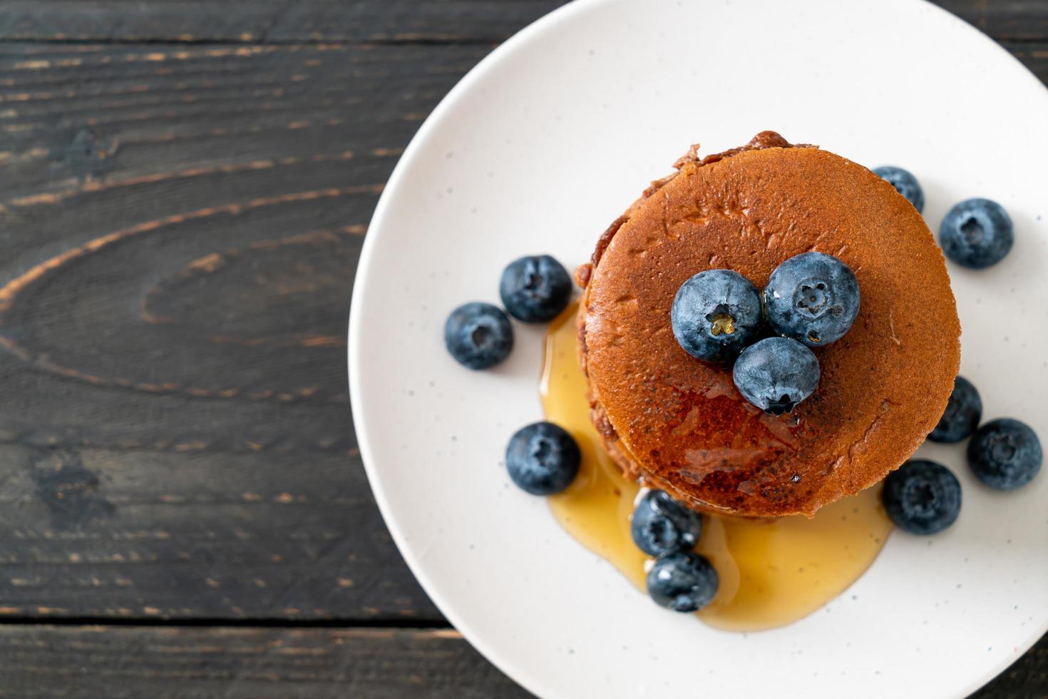 Chocolate pancake stack with blueberry and honey on a plate photo