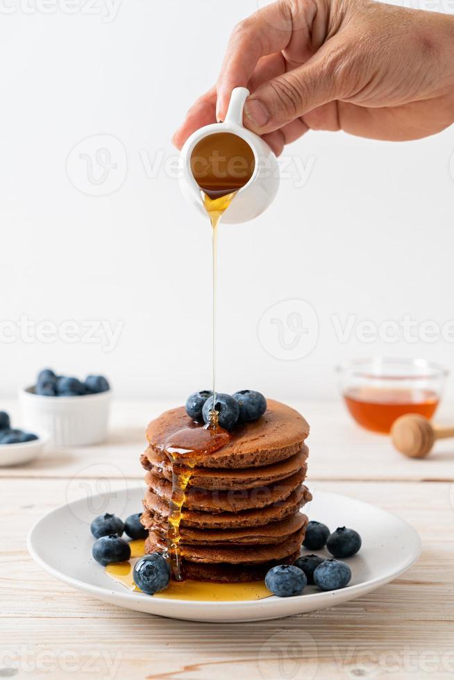 Chocolate pancake stack with blueberry and honey on a plate photo