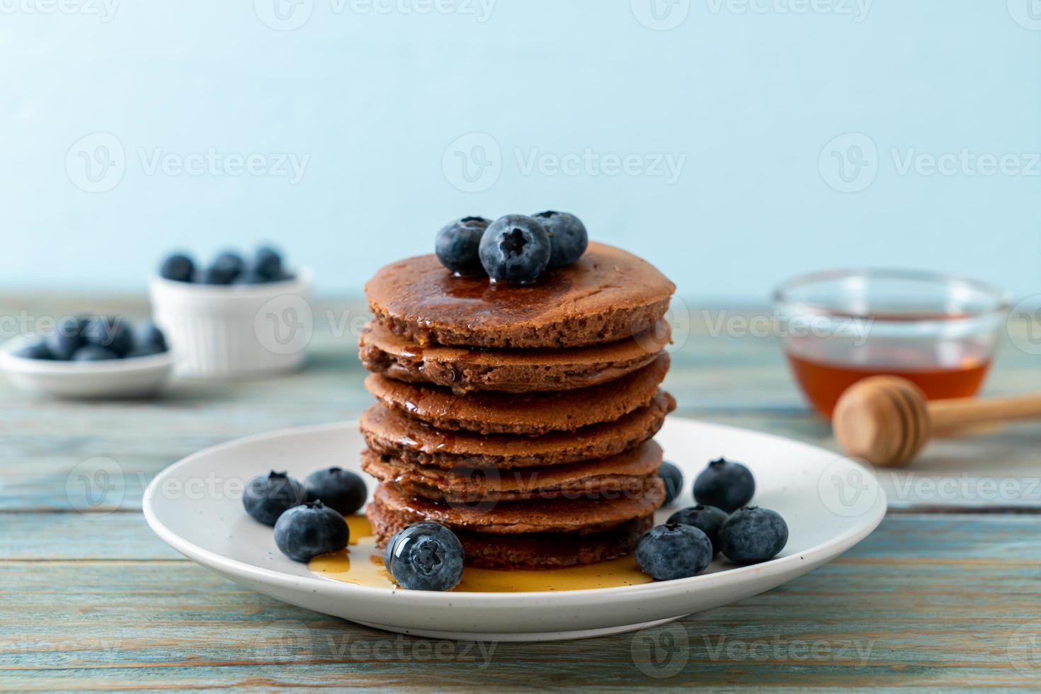 Chocolate pancake stack with blueberry and honey on a plate photo