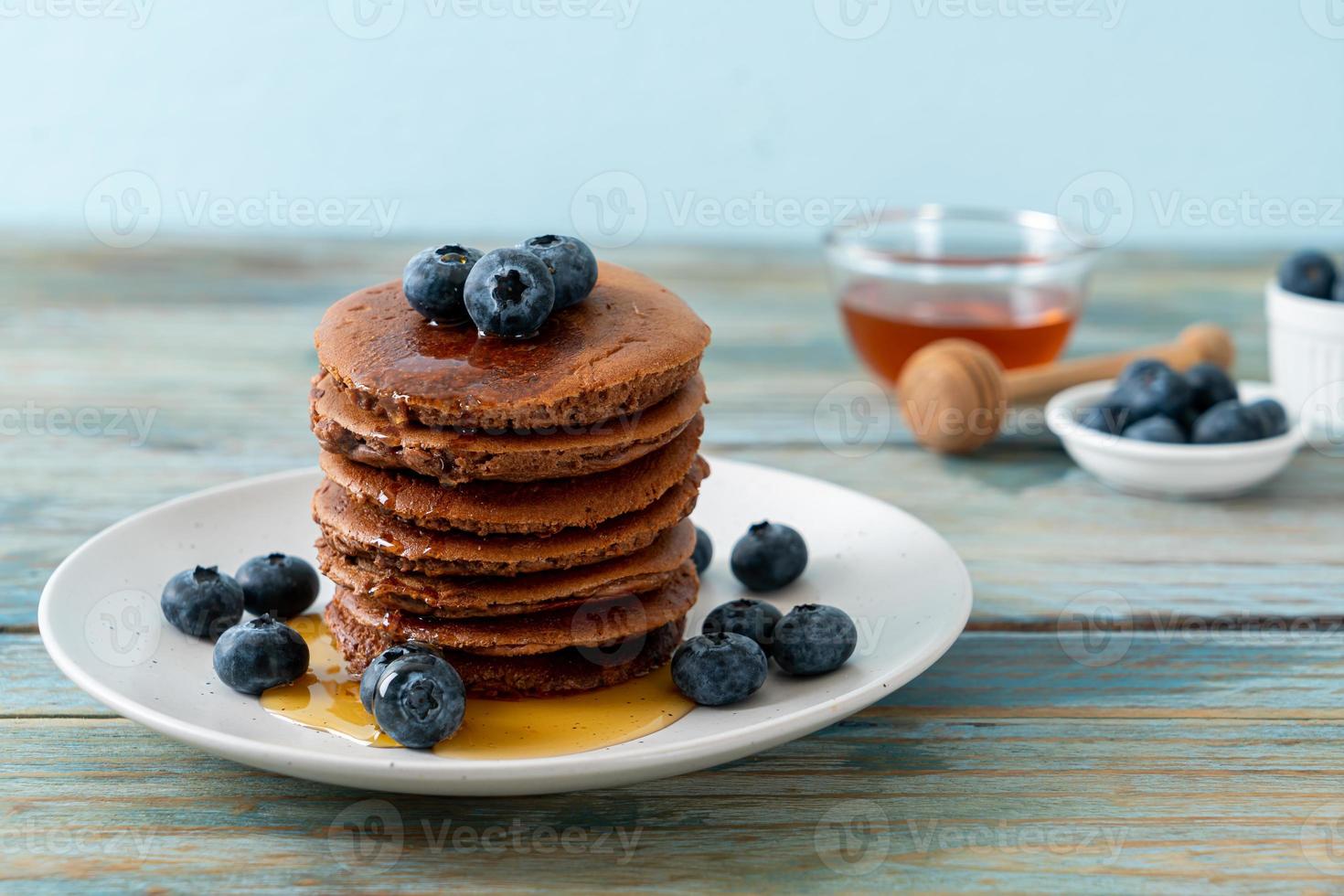 Chocolate pancake stack with blueberry and honey on a plate photo