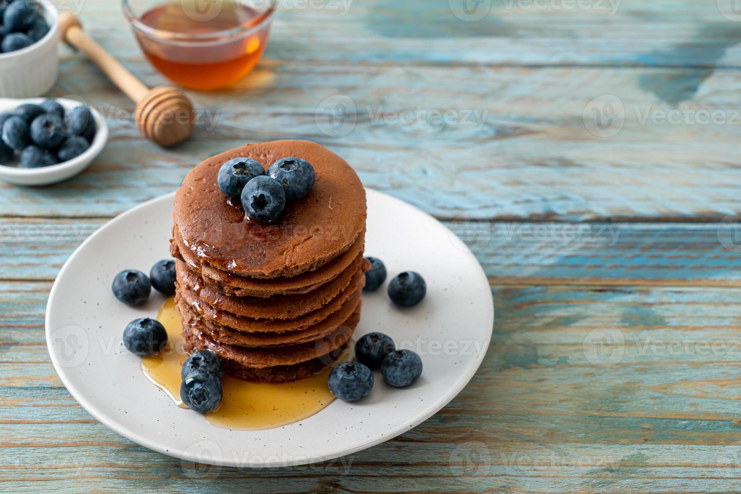 Chocolate pancake stack with blueberry and honey on a plate photo