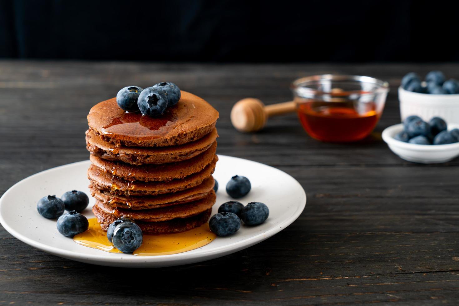 Chocolate pancake stack with blueberry and honey on a plate photo