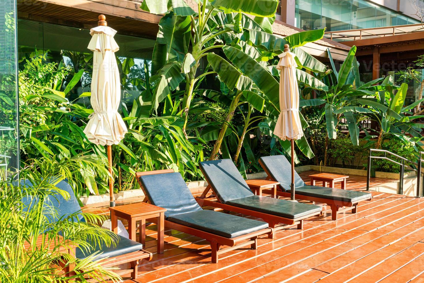 Cama de la piscina vacía alrededor de la piscina con sombrillas y luz solar foto