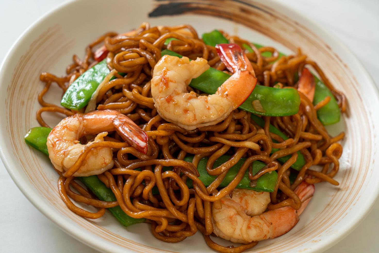 fideos yakisoba salteados con guisantes y camarones - estilo de comida asiática foto