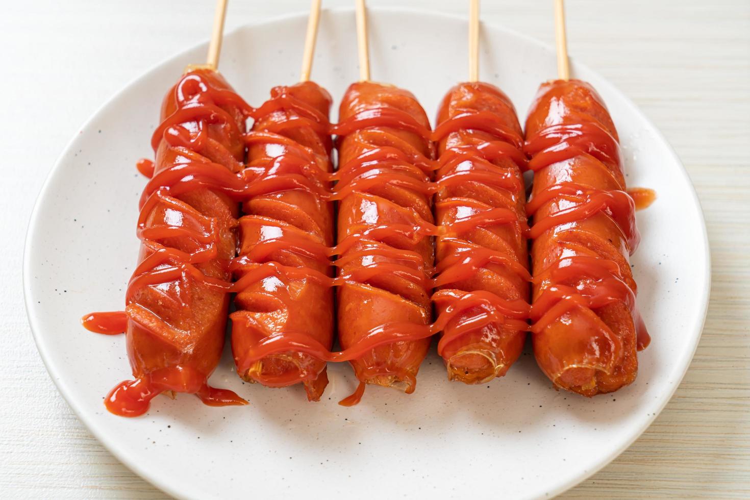 Brocheta de salchicha frita con salsa de tomate en una placa blanca. foto