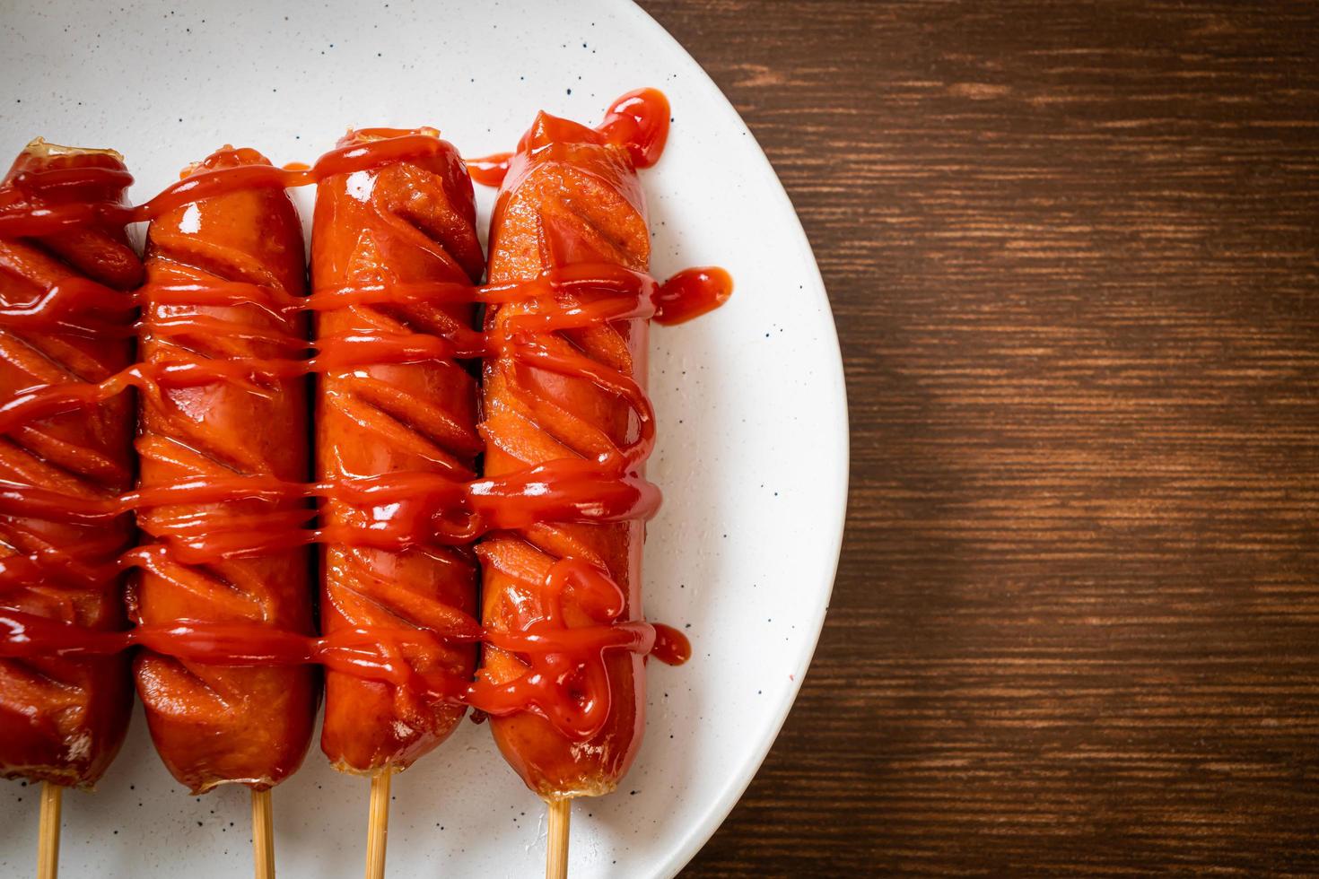 Brocheta de salchicha frita con salsa de tomate en una placa blanca. foto