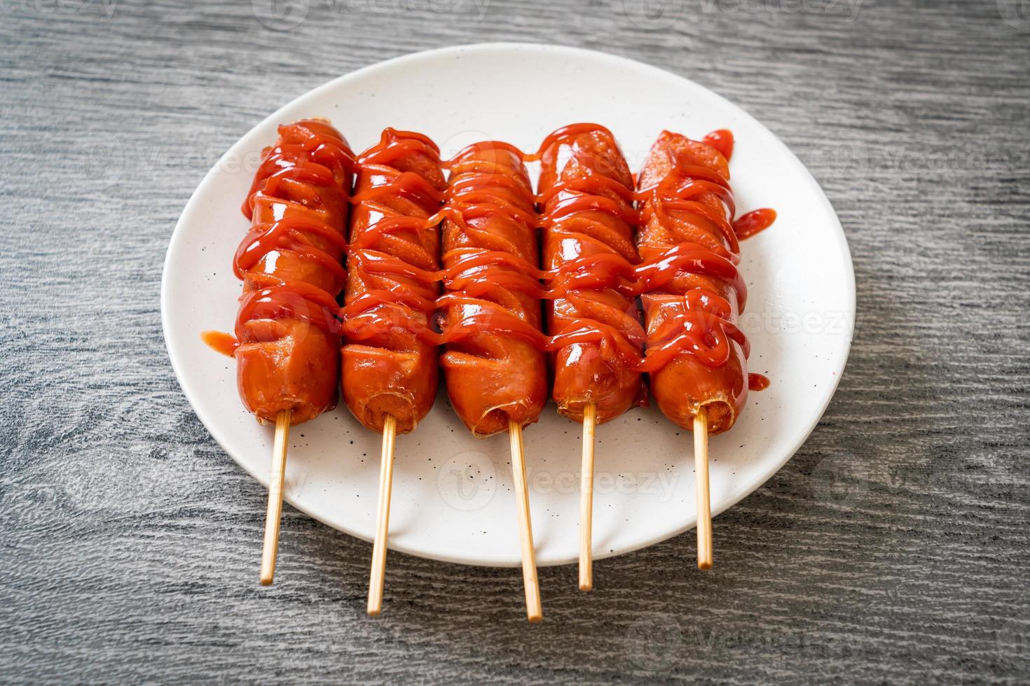 Brocheta de salchicha frita con salsa de tomate en una placa blanca. foto