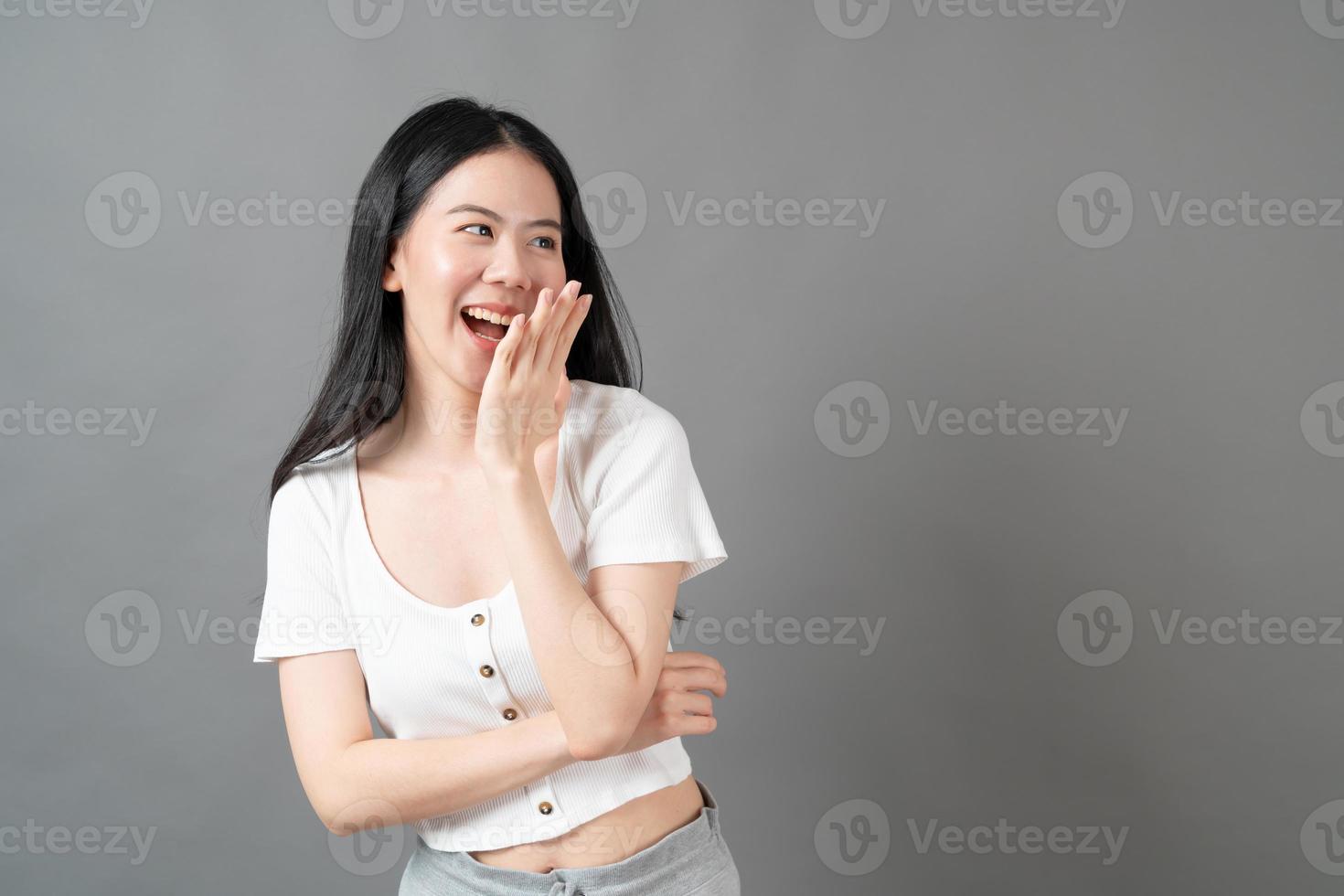 Young Asian woman with happy and smiling face in white shirt on grey background photo