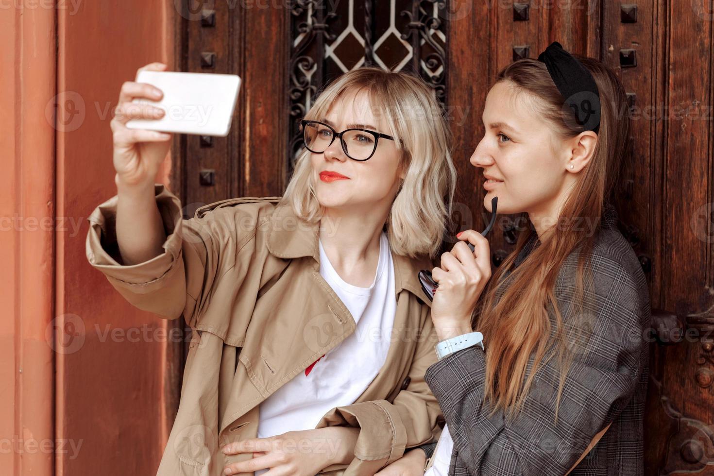 chicas jóvenes tomando selfies por teléfono. Fotos autofotos para redes sociales en teléfonos inteligentes en el fondo de la calle. cara de sorpresa, emociones.