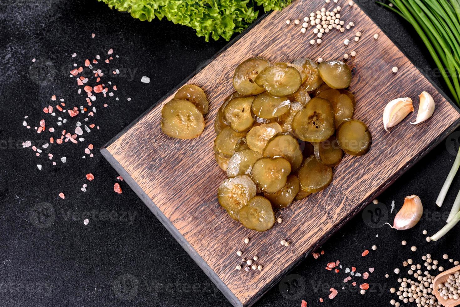 Tasty salty spicy pickled cucumber cut with rings on a wooden cutting board photo