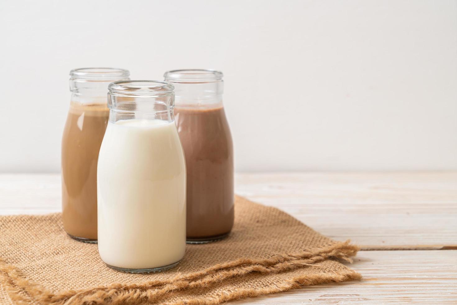 Collection of beverage chocolate milk, coffee and fresh milk in bottle on wood background photo