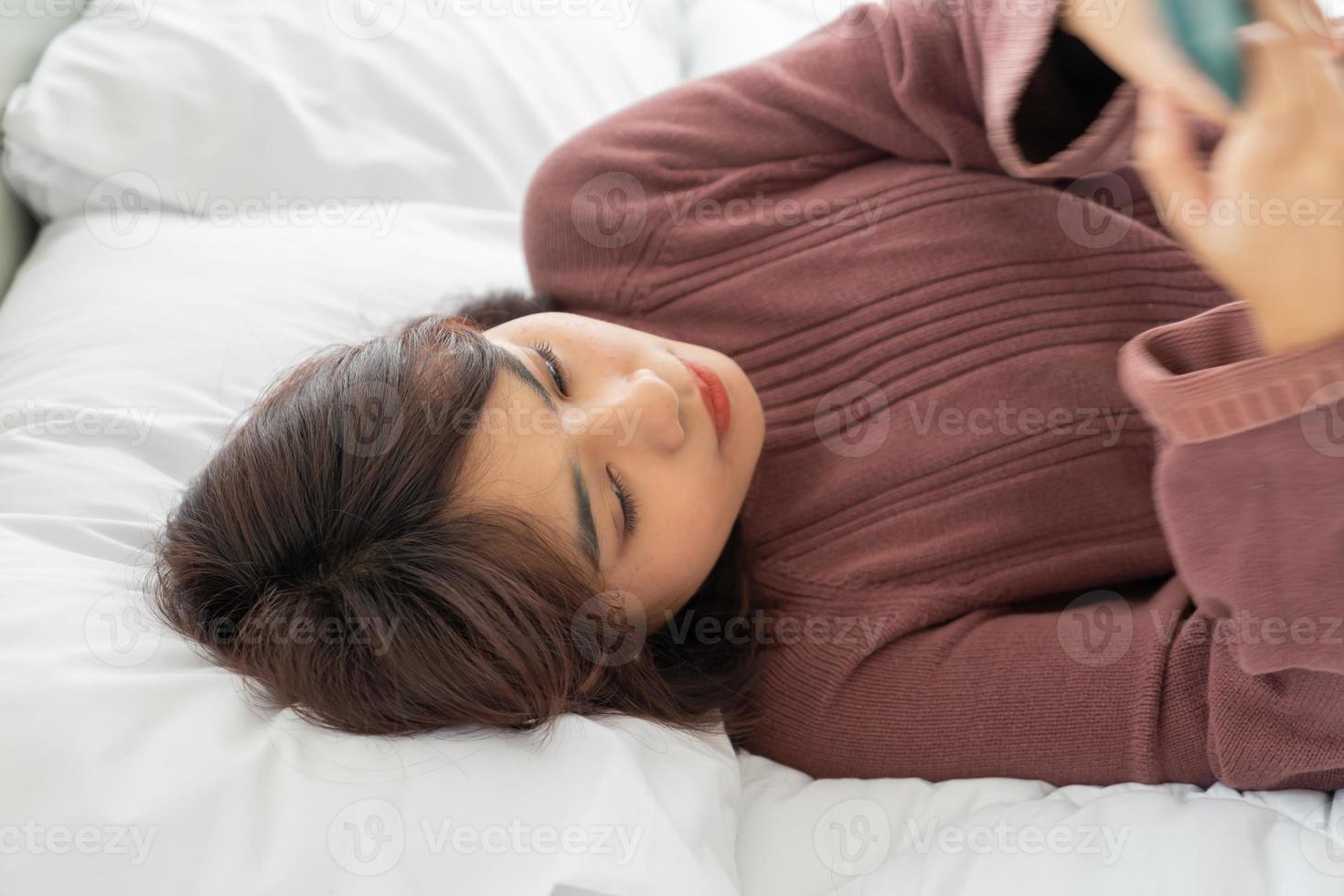 mujer asiática, juego, smartphone, en cama foto