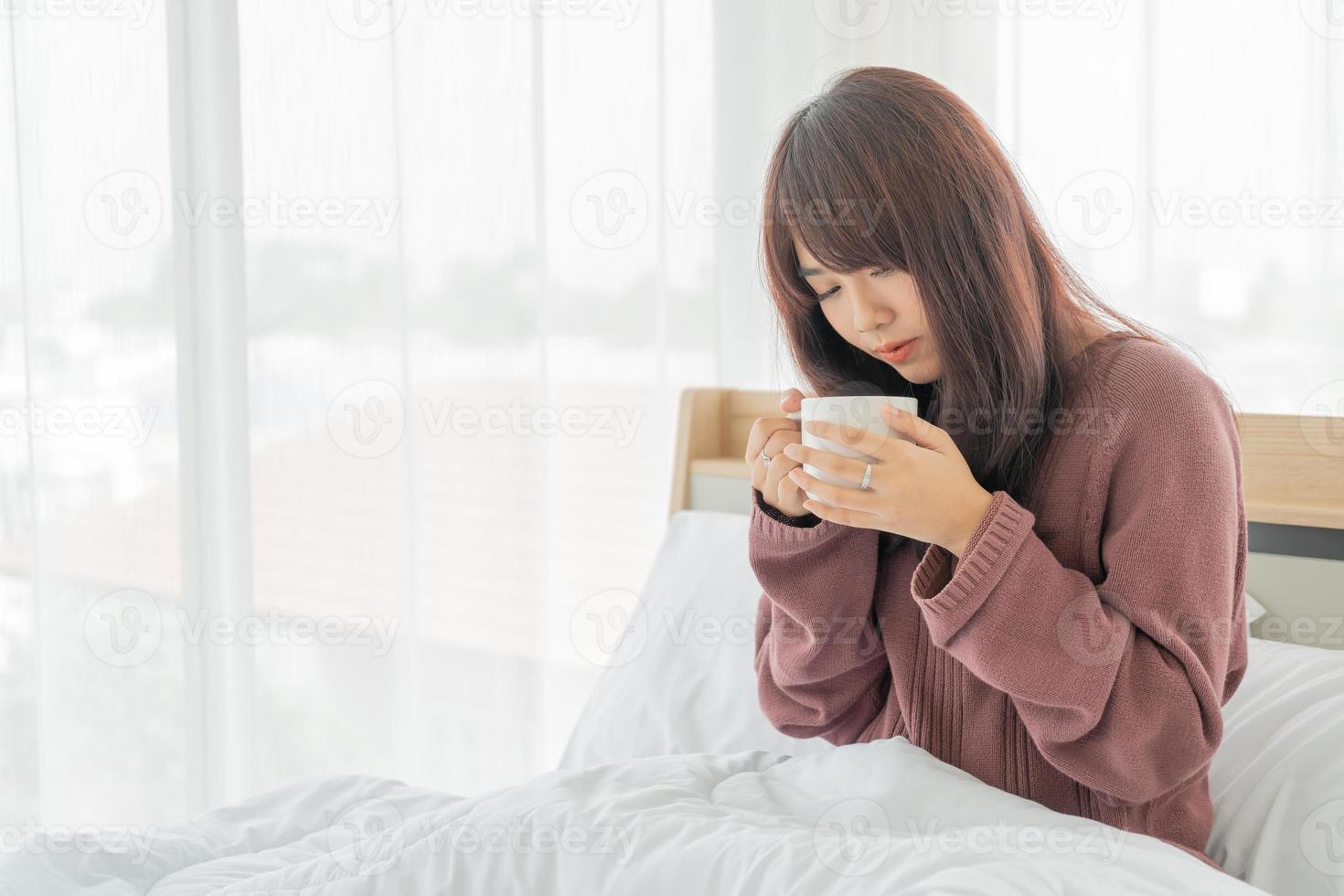 Mujer asiática tomando café en la cama por la mañana foto