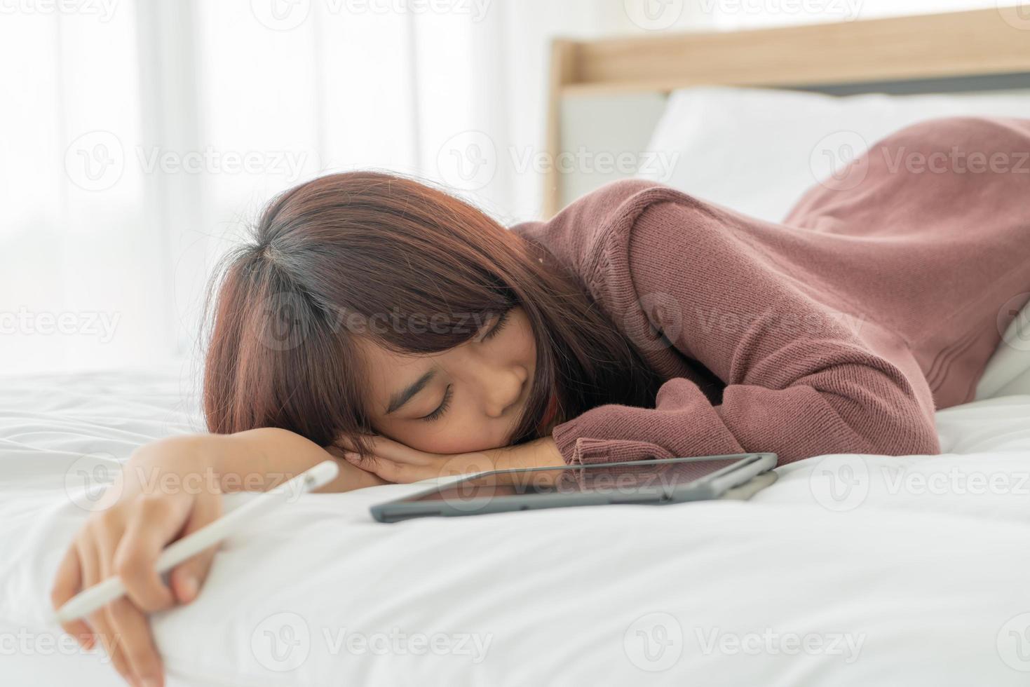 Hermosa mujer asiática que trabaja con la tableta en la cama foto