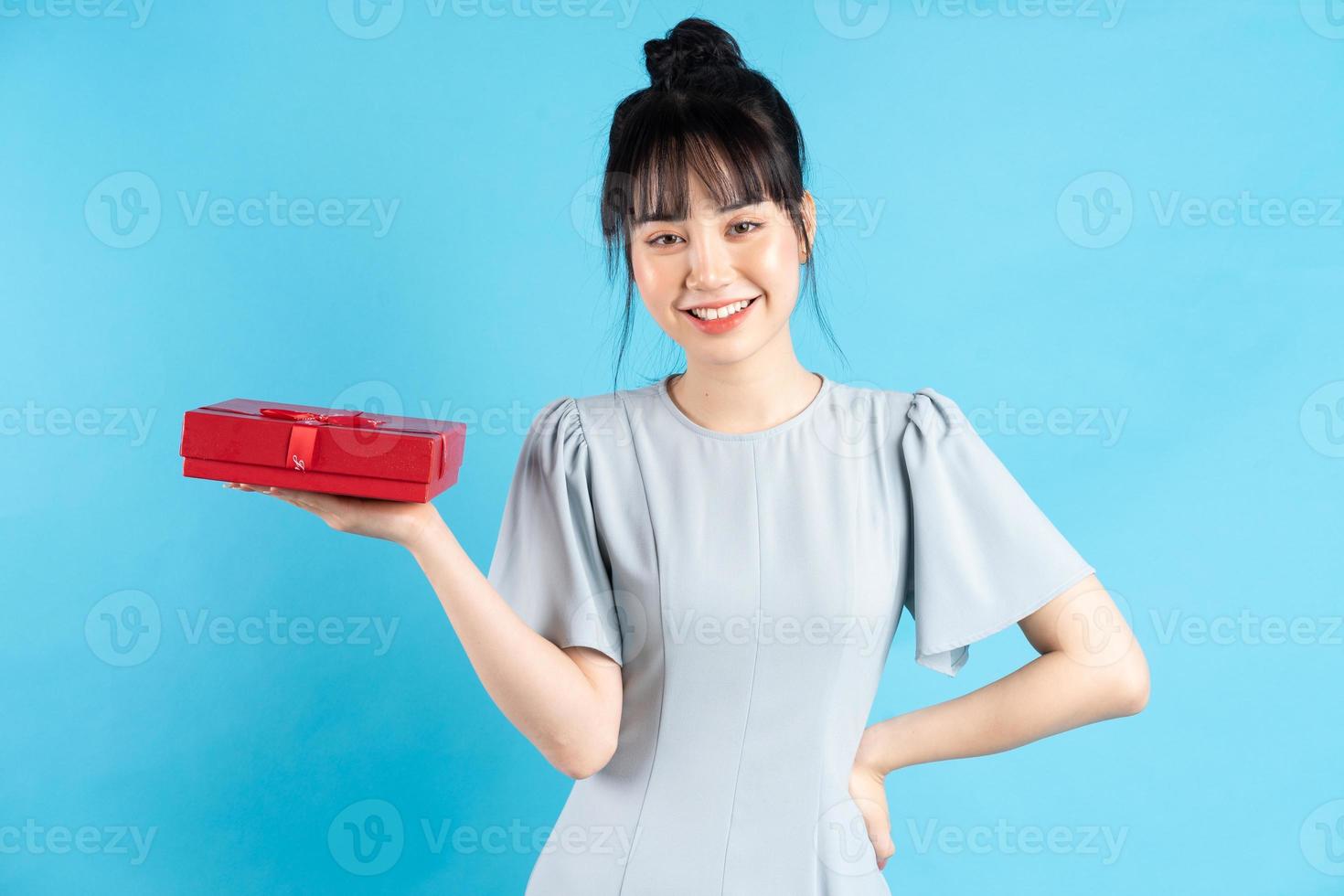 Hermosa mujer asiática sobre fondo azul con una caja de regalo foto