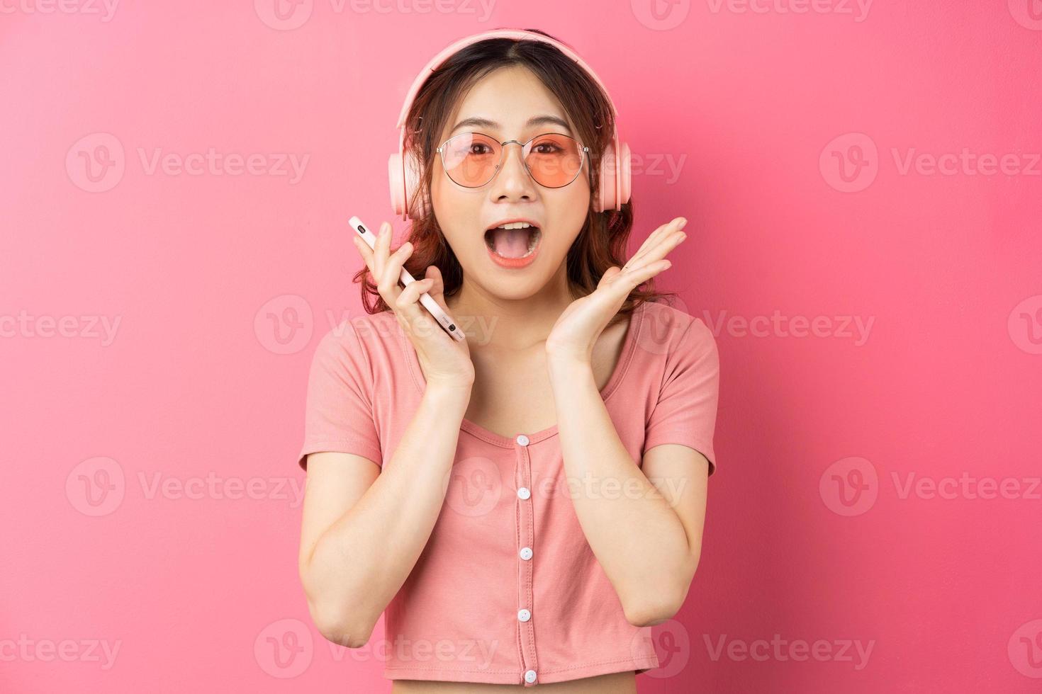 Joven mujer asiática usando el teléfono sobre fondo rosa foto