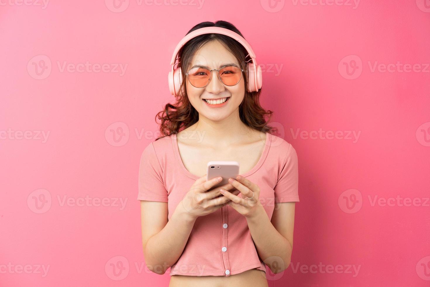 Young Asian woman using the phone on pink background photo