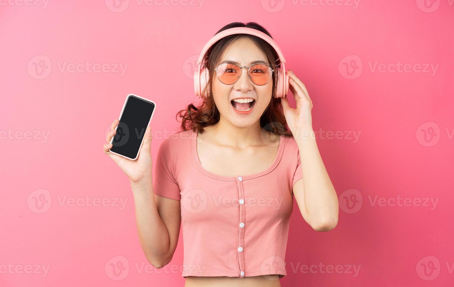 Joven mujer asiática usando el teléfono sobre fondo rosa foto