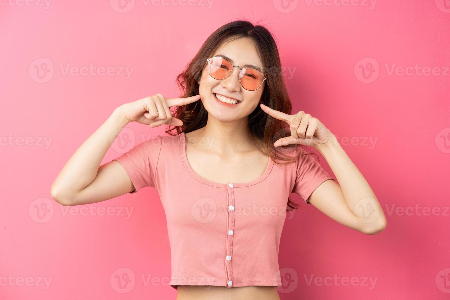 Young Asian woman wearing glasses with cheerful expression on a pink background photo