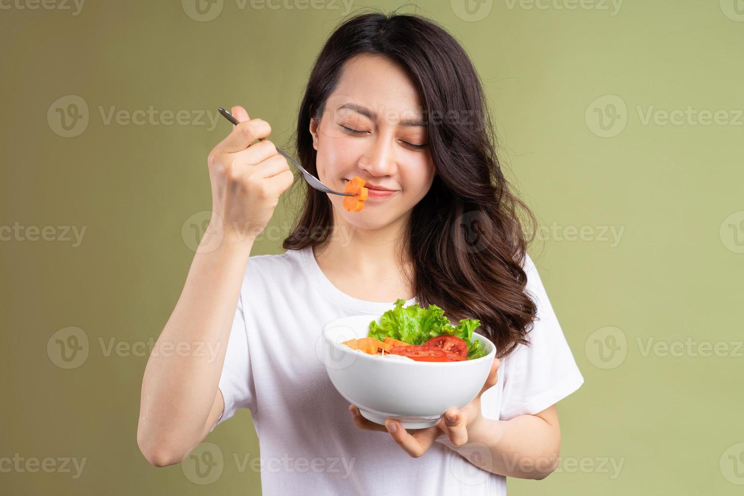 Alegre joven asiática comiendo alimentos saludables en el fondo foto