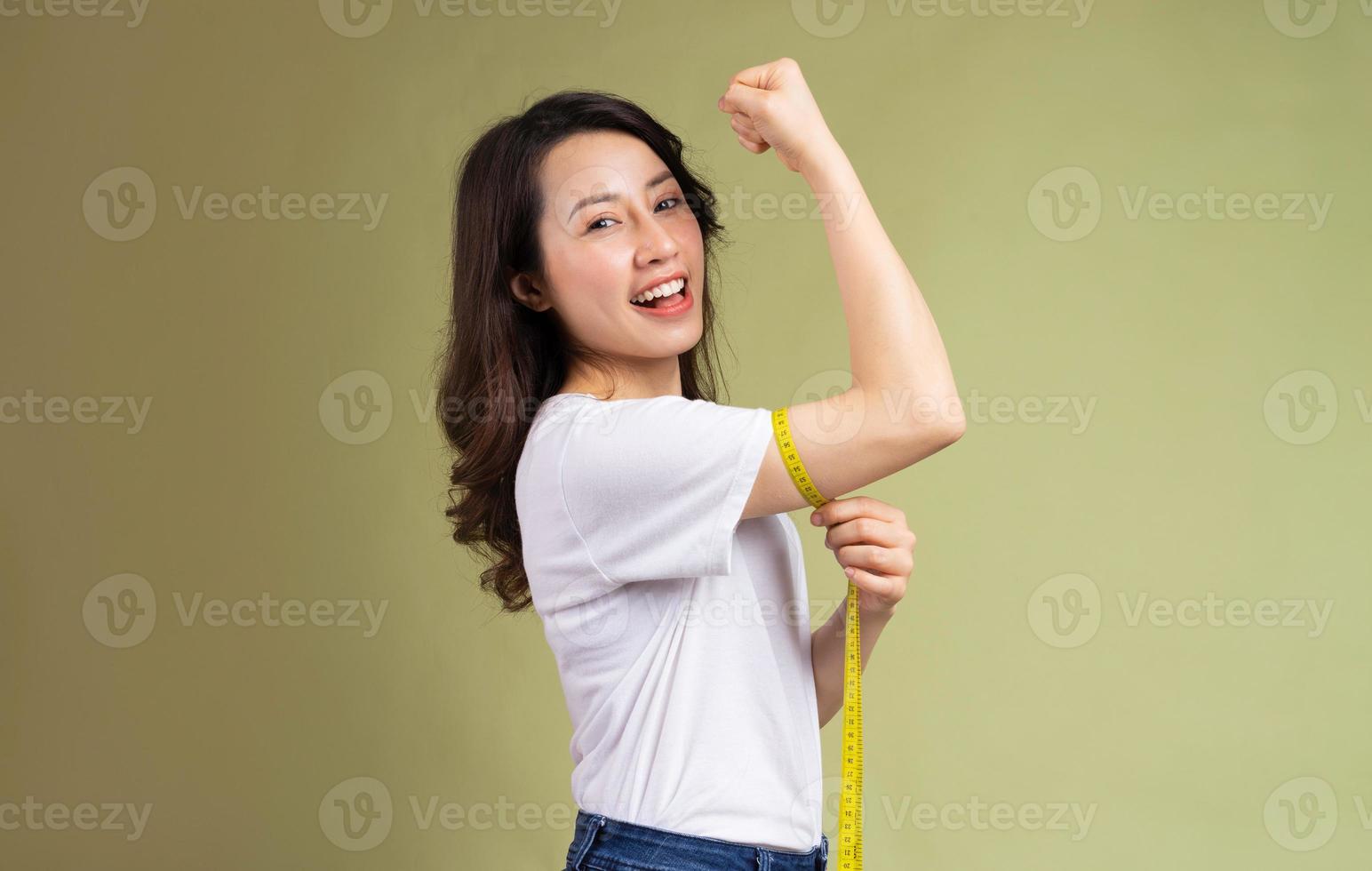 Joven asiática sosteniendo felizmente la cinta métrica después de perder peso foto