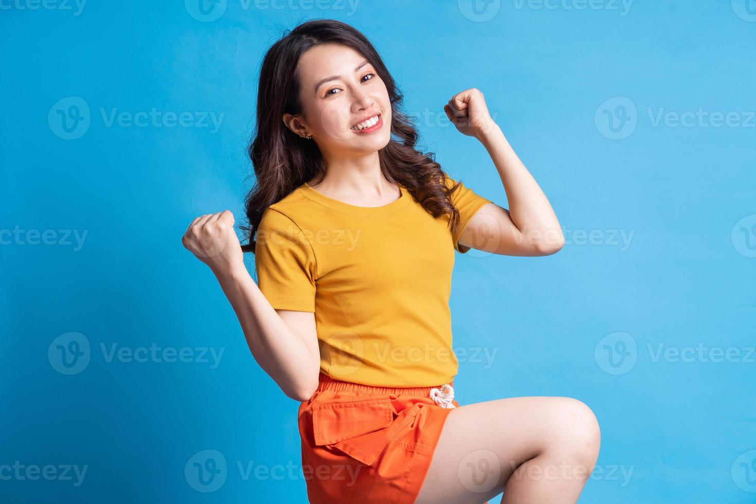Hermosa mujer asiática con estilo activo sobre fondo azul. foto