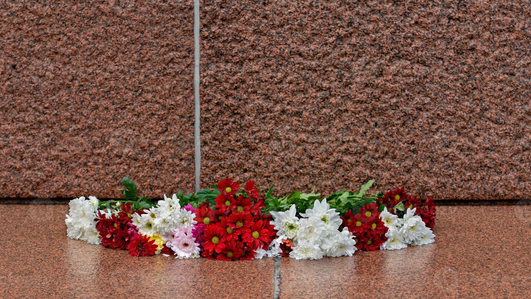 Letonia 100 años. Composiciones de flores rojas y blancas en el monumento a la libertad en la ciudad de Riga, Letonia. foto