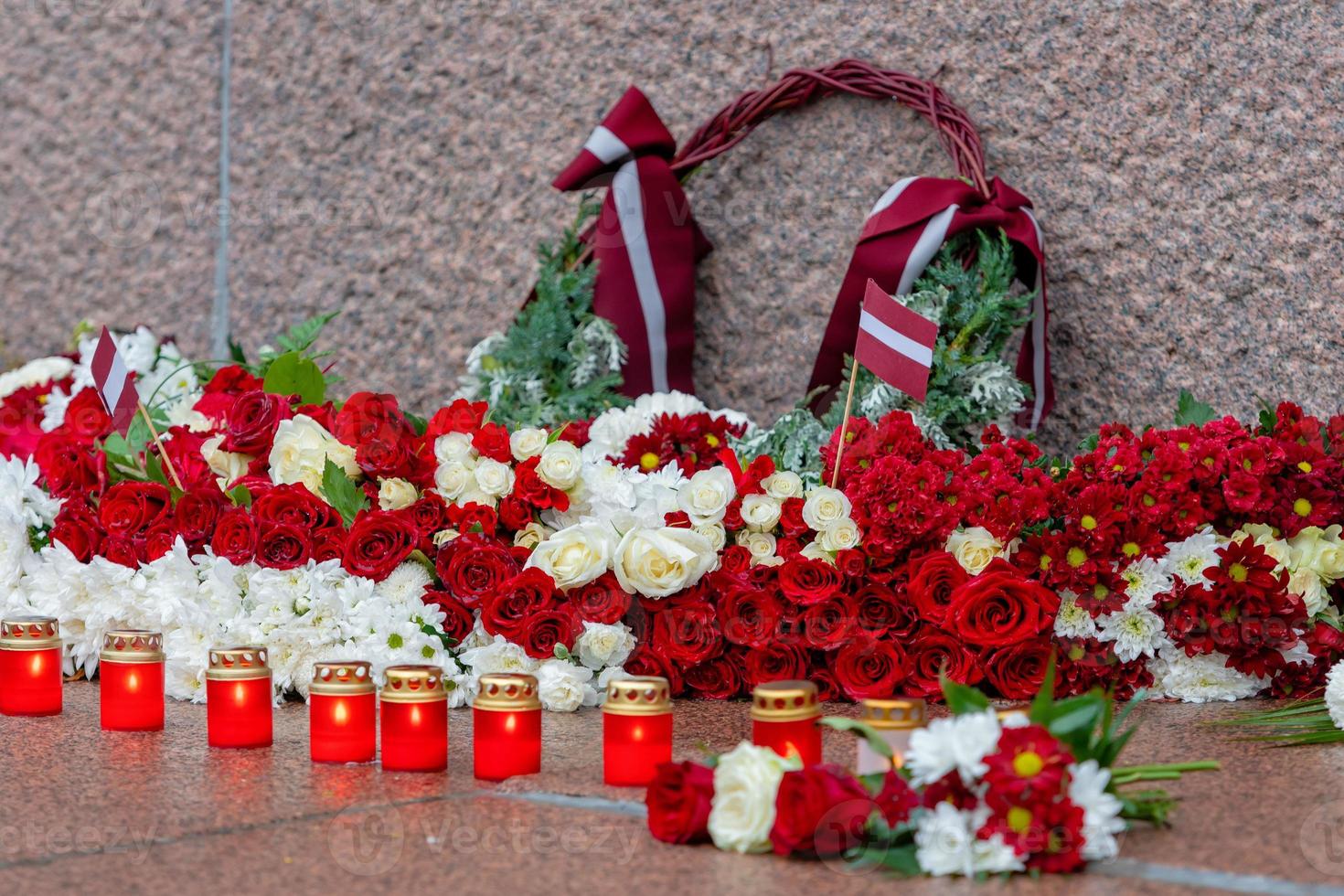 Letonia 100 años. Composiciones de flores rojas y blancas en el monumento a la libertad en la ciudad de Riga, Letonia. foto