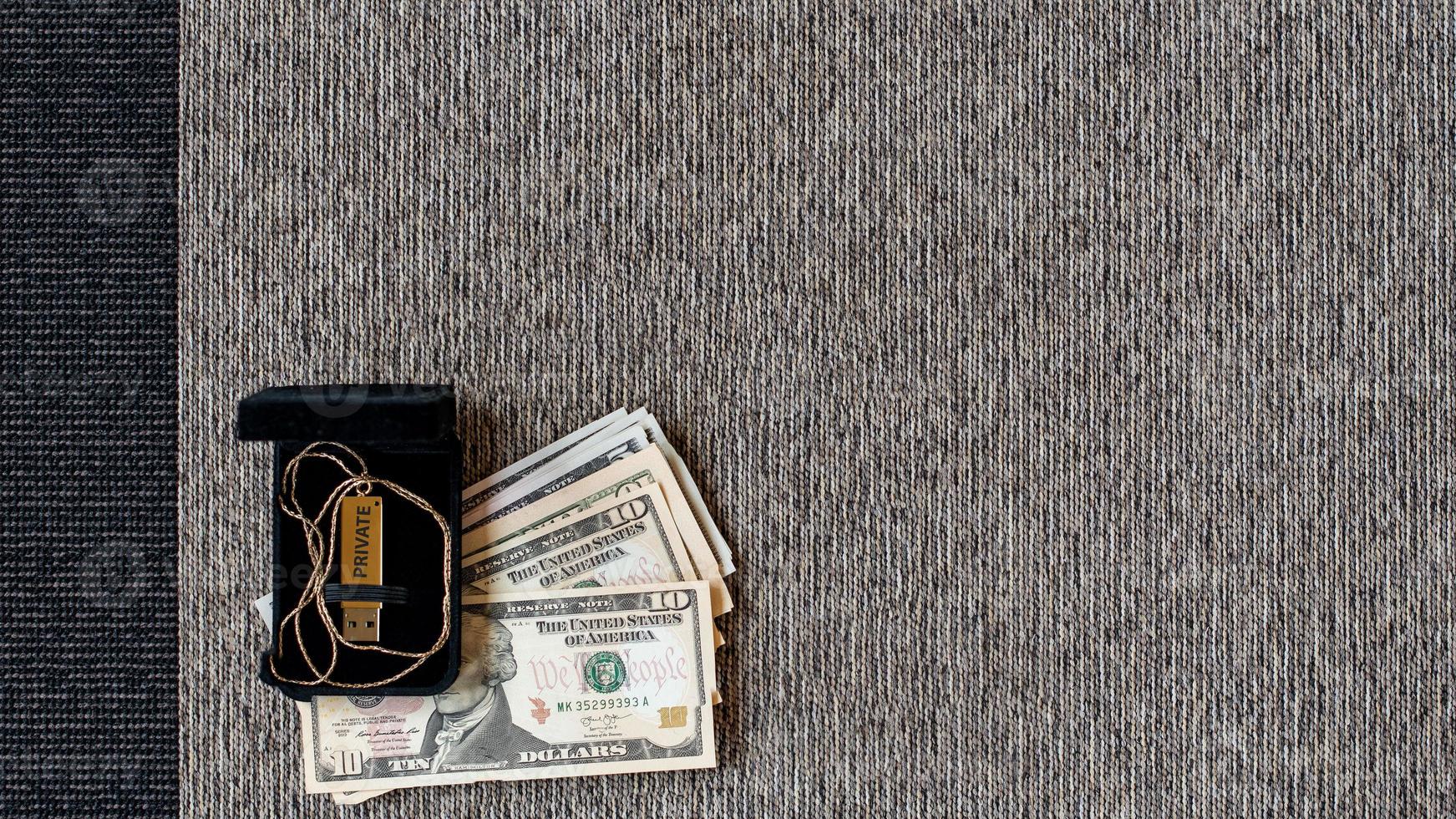 USB disk with private data and money on a two-tone textile background. photo