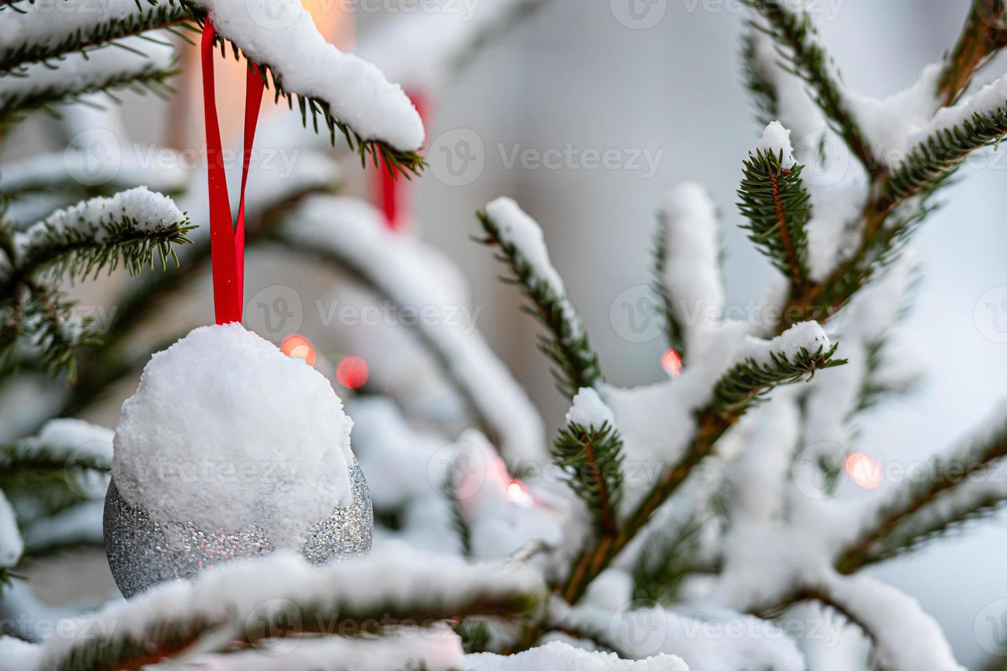 Colorful decorations on snow-covered Christmas tree branches photo