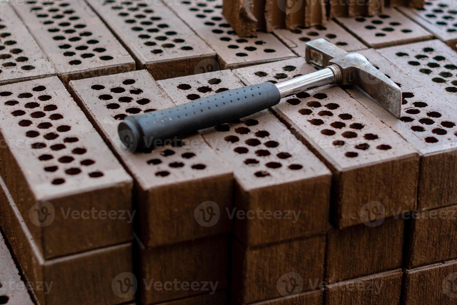 A hammer is laid on a red brick stack. photo