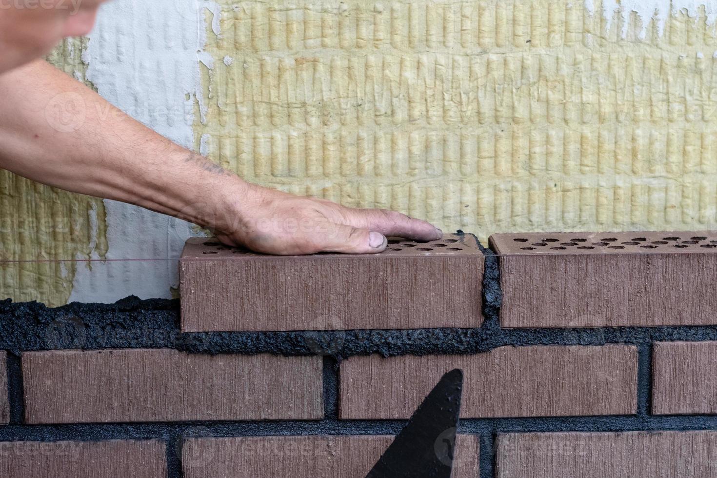 Bricklayer worker installing bricks on construction site. photo