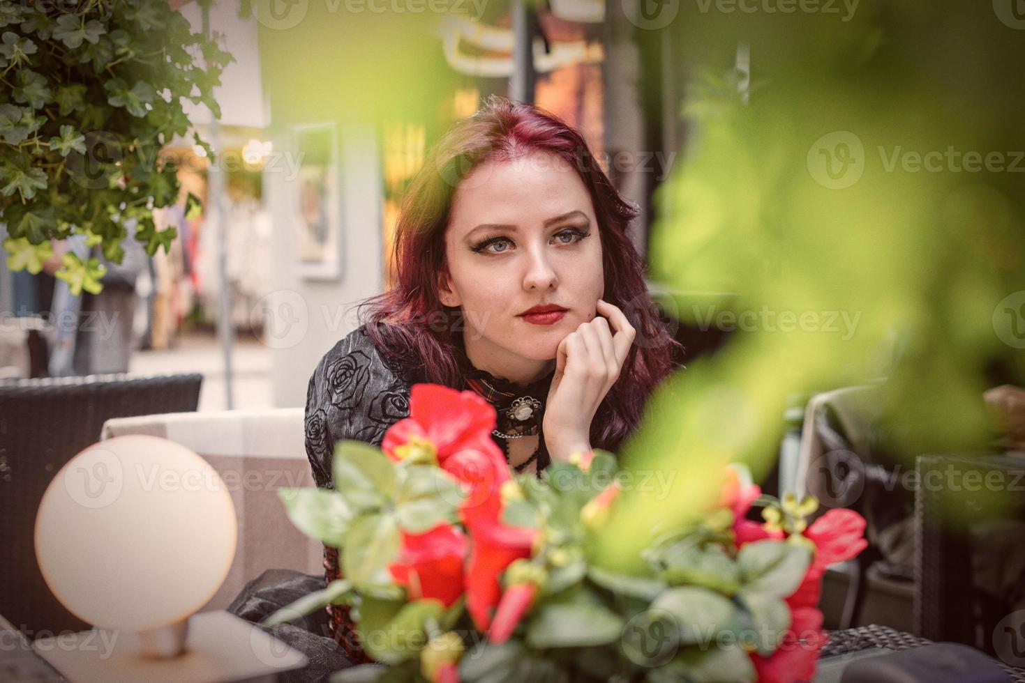 joven hermosa pelirroja sentada en un café al aire libre vestida con ropa de moda retro. foto