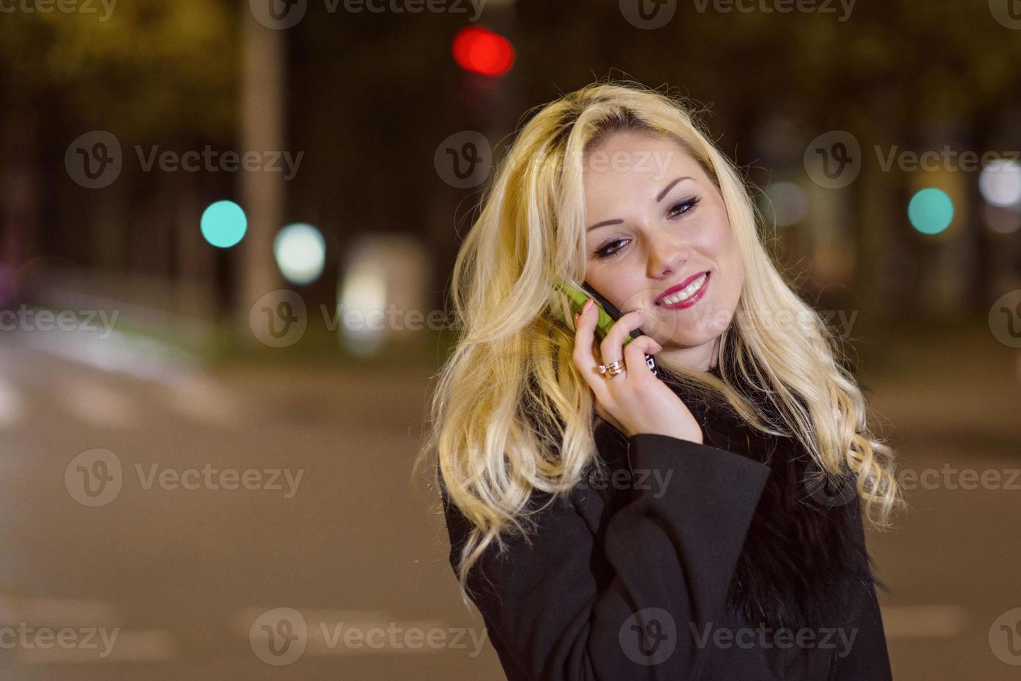 mujer hermosa, rubia en las luces del coche en la ciudad de noche. foto