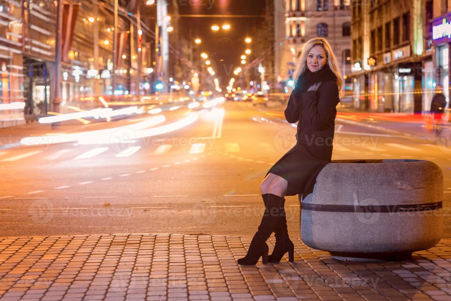 Beautiful, blonde woman in car lights in the night city. photo
