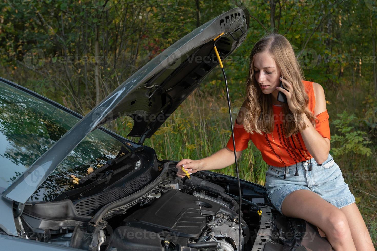 Mujer joven cerca de coche roto hablando por teléfono necesita ayuda - imagen foto
