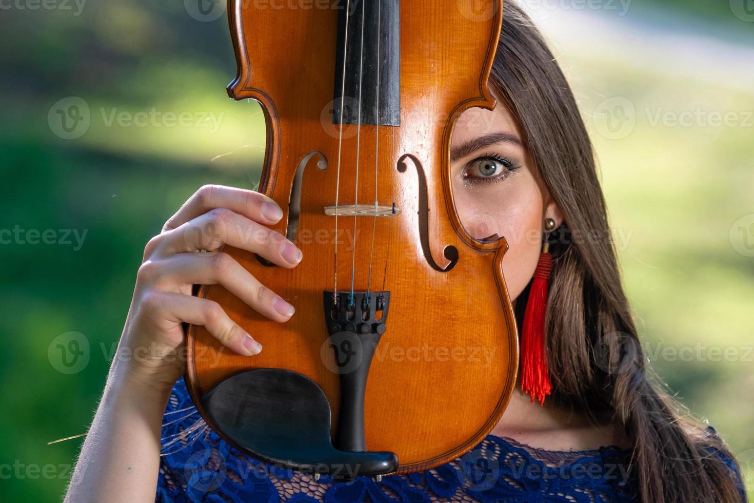 Portrait of a positive young woman. Part of the face is covered by the neck of the violin - image photo