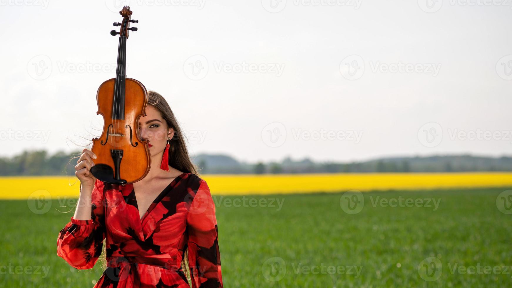 Portrait of a positive young woman. Part of the face is covered by the neck of the violin - image photo