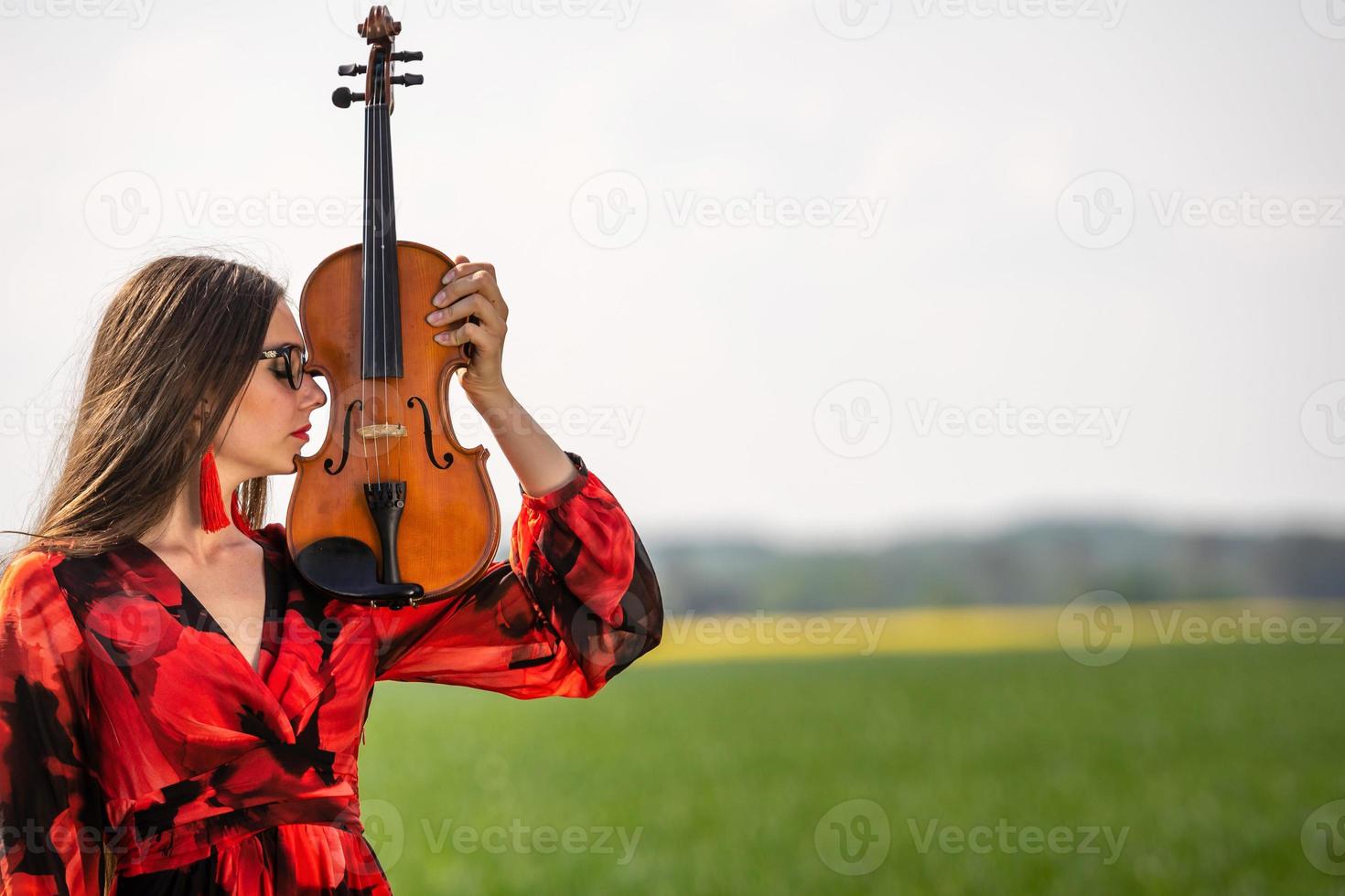 Portrait of a positive young woman. Part of the face is covered by the neck of the violin - image photo