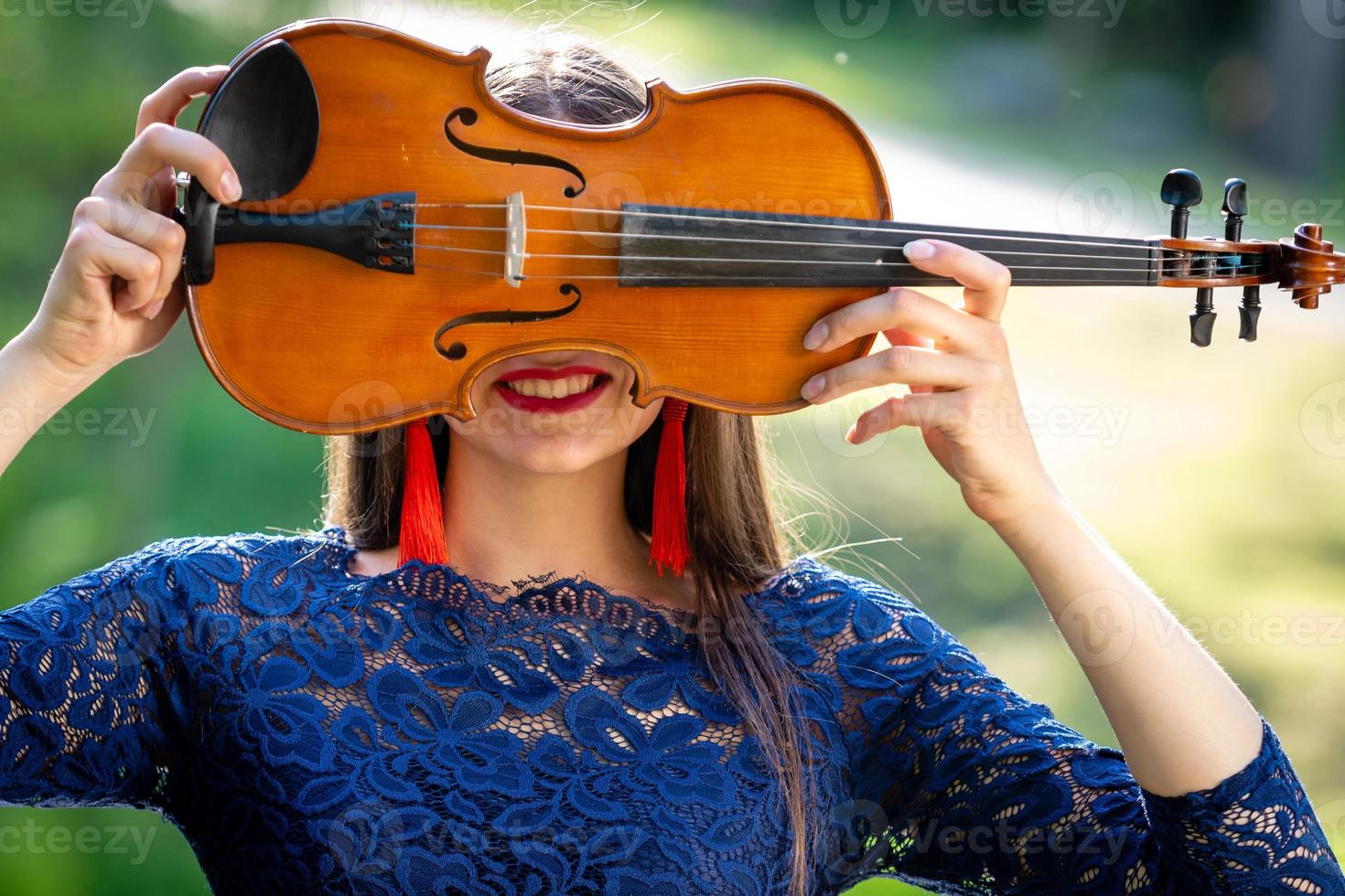 retrato de una mujer joven positiva. parte de la cara está cubierta por el cuello del violín - imagen foto