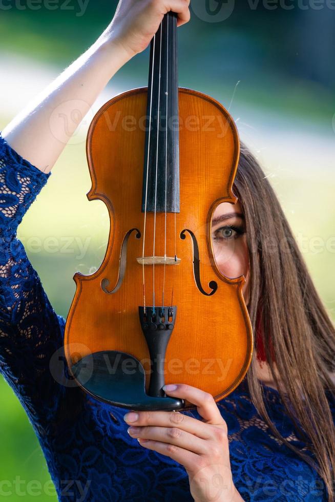 retrato de una mujer joven positiva. parte de la cara está cubierta por el cuello del violín - imagen foto