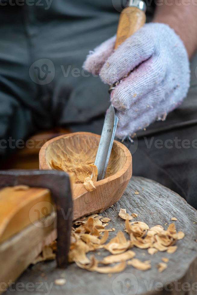 artesano demuestra el proceso de fabricación de cucharas de madera foto